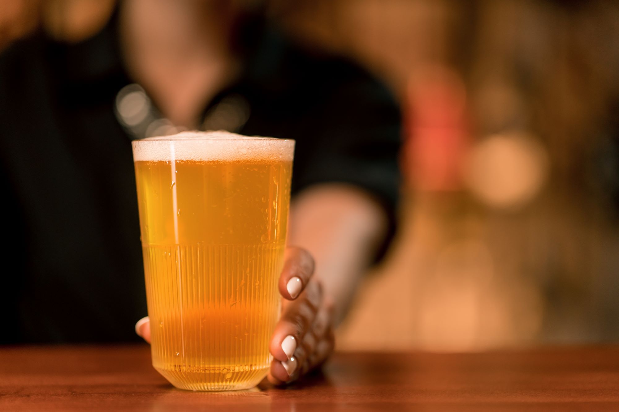 close up of a woman's hand holding a glass of beer