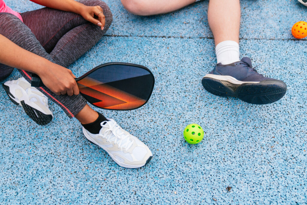Group of friends holding paddles, getting ready for a pickleball match on a blue court